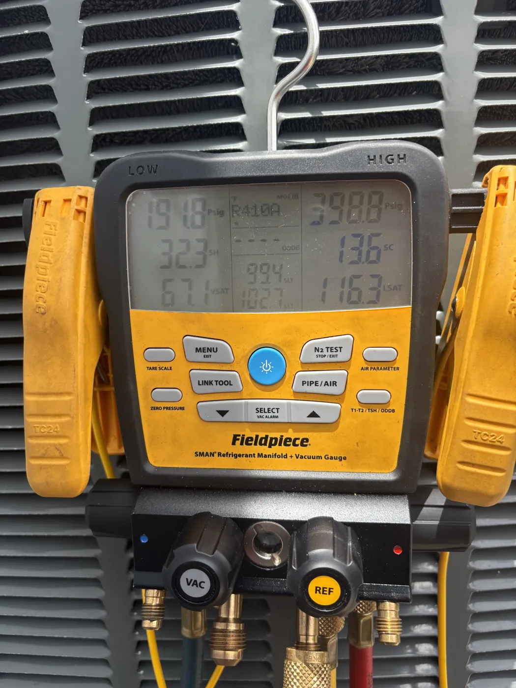 A digital refrigerant manifold connected to a system, showing high and low side pressures and saturation temperatures