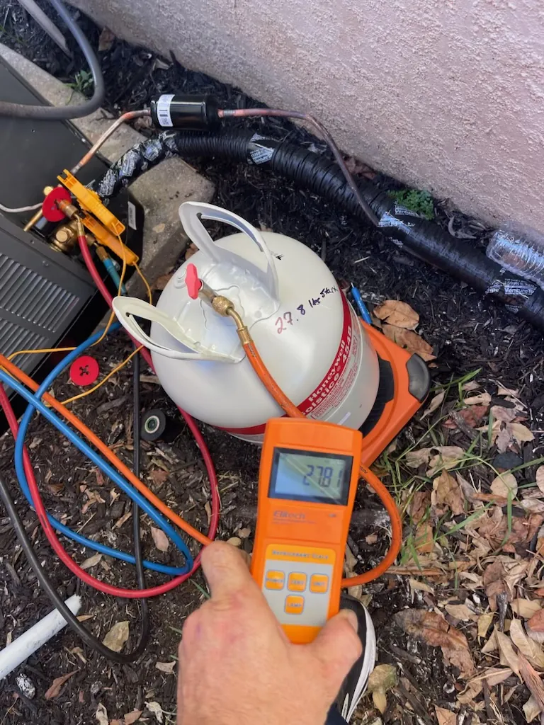 A refrigerant cylinder sitting on a digital charging scale with hoses connected during a charge